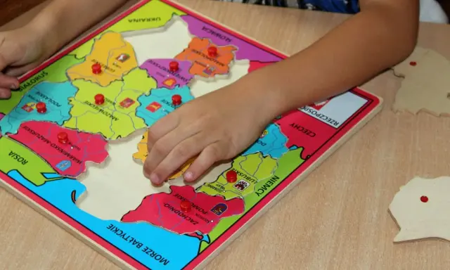 Dziecko układa puzzle z mapą Polski, ucząc się regionów. To świetne gry dydaktyczne w przedszkolu.