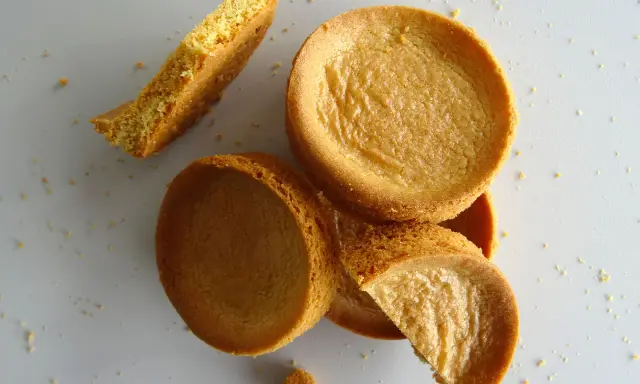 Des morceaux de sablé breton dorés, certains entiers, d'autres brisés, éparpillés sur un fond clair.