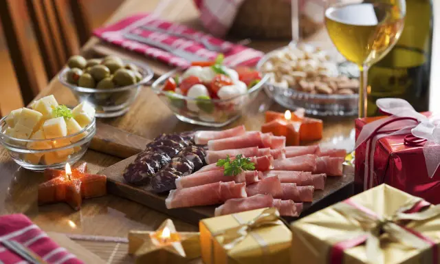 Eleganckie menu na sylwestra w domu: wędliny, sery, oliwki, pomidorki z mozzarellą, orzechy, wino i prezenty.