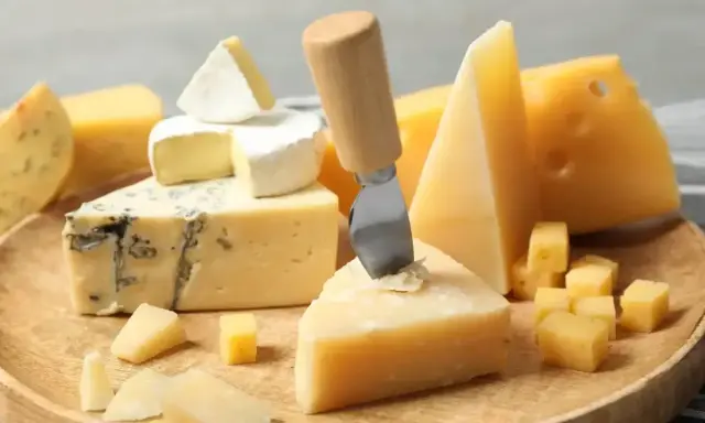 Deska serów: pleśniowy, camembert i twarde sery, w tym ser sałatkowy pokrojony w kostkę.