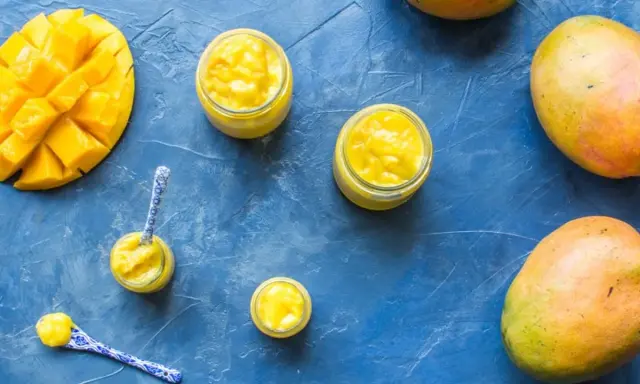 Délicieux curd mangue dans des petits pots, avec des mangues fraîches et des cuillères décorées. Un délice tropical !
