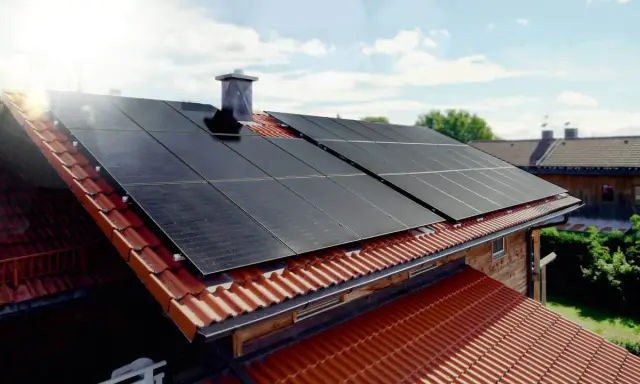 Solceller tillverkning på ett tegeltak. Solen skiner på panelerna som fångar upp energin.