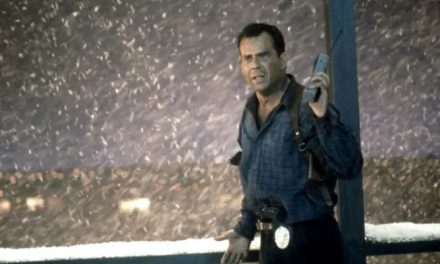 Bruce Willis som John McClane, mitt i snöstormen, med en gammal mobiltelefon i handen. En ikonisk scen från rollistan i Die Hard 2.