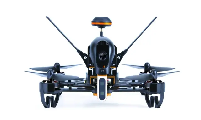 Ich sehe aus der **first person view** auf einen schwarzen Quadrocopter mit orangefarbenen Akzenten. Seine Kamera ist bereit für den Flug.