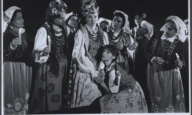 Grupa kobiet w tradycyjnych strojach, z zapalonymi świecami, przygotowuje się do klimina wesele.