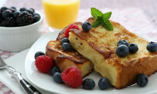 Deliciosa french toast receta, dorada y esponjosa, adornada con frambuesas, arándanos y menta. Un desayuno perfecto.