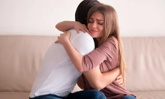 Mujer llorando abraza a hombre. Podría ser un ejemplo de frases de disculpas por no asistir a una boda.