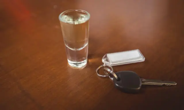 Kieliszek z alkoholem i kluczyki do samochodu. Pamiętaj, że kara za jazdę po pijanemu jest surowa.