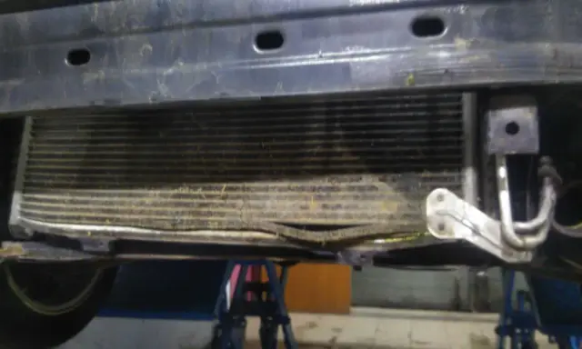 Uszkodzony skraplacz klimatyzacji objawy: zgięte żeberka, widoczne uszkodzenia mechaniczne.
