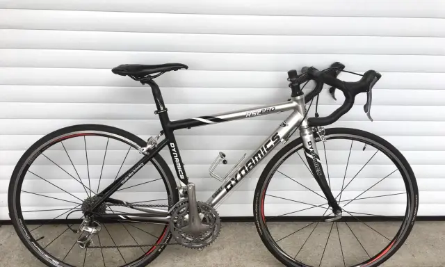 Silbernes Rennrad DYNAMICS RSL COMP mit schwarzen Akzenten, bereit für die nächste Fahrt.