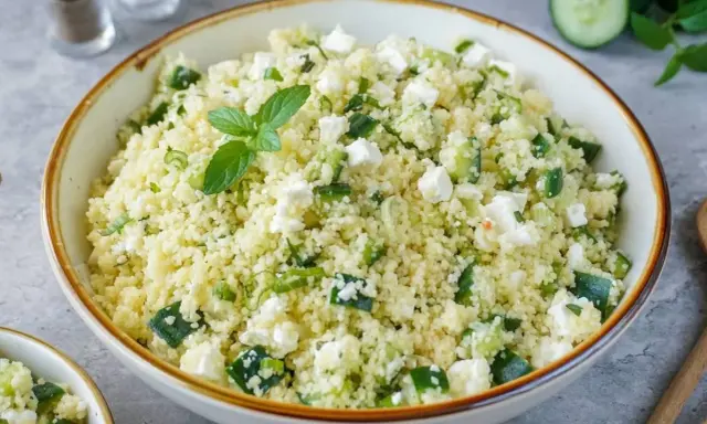 Frischer Couscous Salat mit Feta, Gurken und Minze, garniert mit einer Minzblatt.