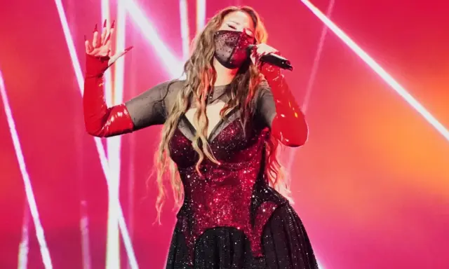 Artist med mask och röda handskar sjunger på scen. Kanske en försmak av Eurovision 2026 tid?