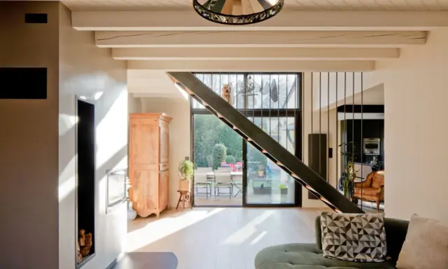 Rénovation d'une maison année 70 : avant, un style désuet ; après, un espace lumineux avec escalier moderne, poêle design et vue sur jardin.