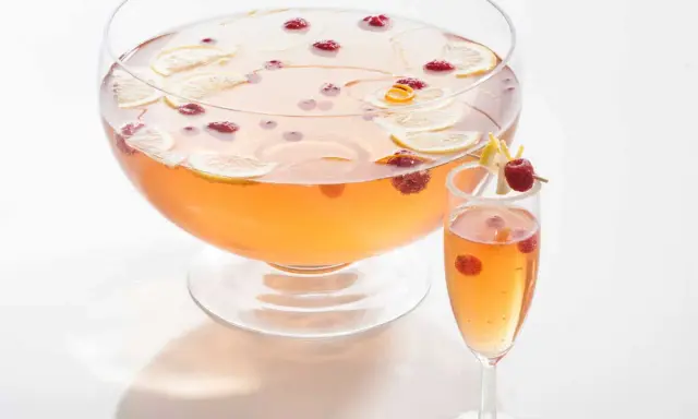 Un grand bol de punch rose avec des tranches de citron et des framboises, prêt pour une recette de soupe champenoise.