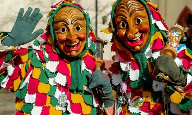 Due maschere di carnevale in Italia, con costumi colorati e volti grotteschi, salutano festanti.