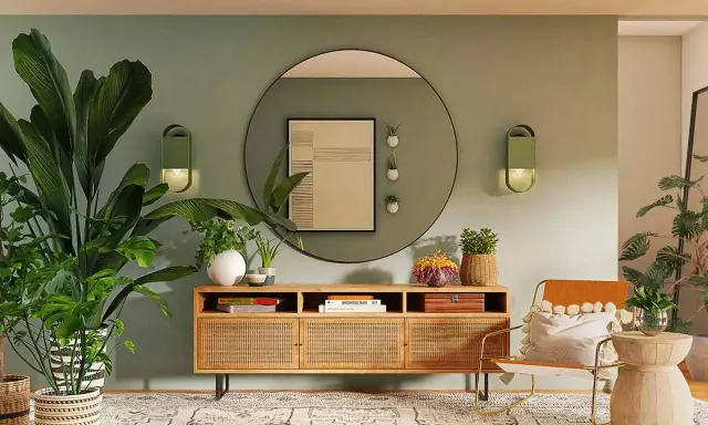 Ingresso accogliente con piante rigogliose, mobile in legno con rattan e un'opera d'arte astratta. La parete verde crea una **tabella colori caldi** rilassante.