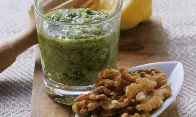 Frisches Petersilienpesto im Glas, daneben Walnüsse und eine Zitronenhälfte. Perfekt für Petersilie Rezepte.