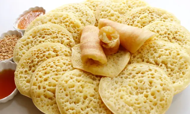 Assiette de crêpes mille trous, garnies de miel et de cacahuètes concassées. Un délice à déguster !