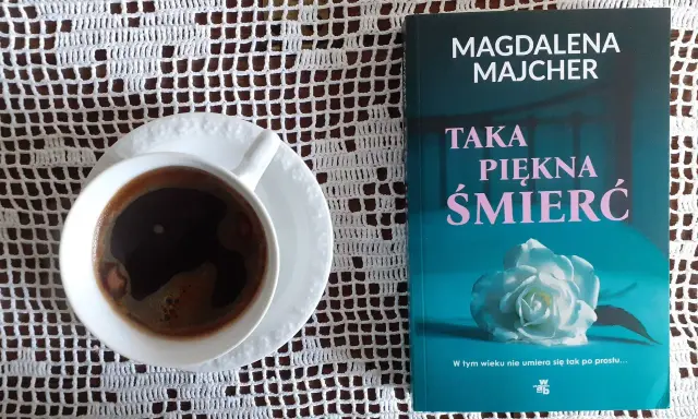 Kawa i książka Magdaleny Majcher "Taka piękna śmierć" na białej serwetce.