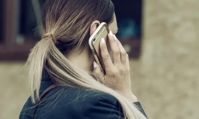 Kobieta rozmawia przez telefon, martwiąc się, czy pracodawca może odmówić urlopu na żądanie.