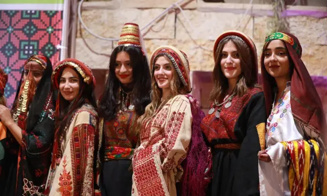 Six young women proudly showcase traditional Palestinian attire, highlighting the vibrant artistry of Palestinian designers.