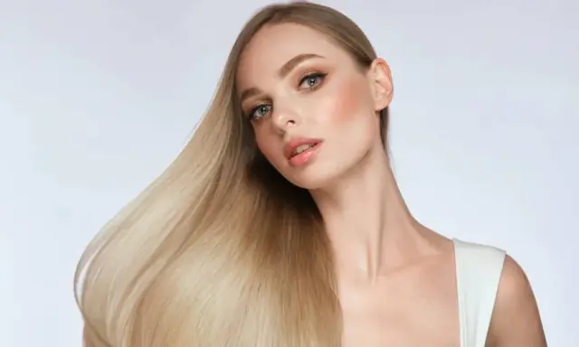 Blonde Frau mit glänzendem Haar, das durch Proteine gestärkt wurde.