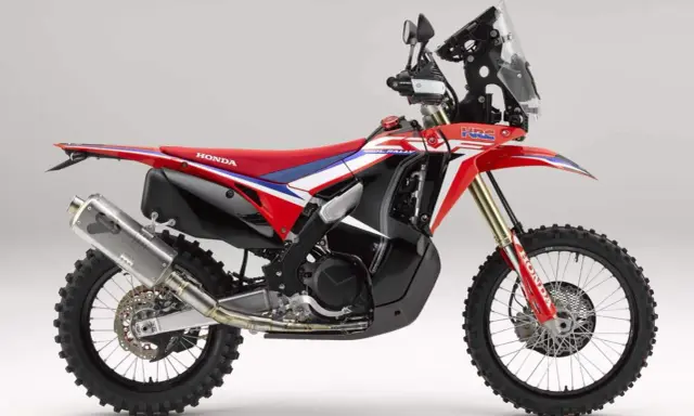 Czerwono-biały motocykl Honda CRF 450 Rally z czarnymi akcentami, gotowy na rajdowe wyzwania.