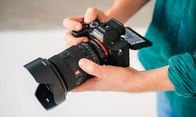 Dłonie trzymają aparat Sony a7r5 z obiektywem 24-70mm.