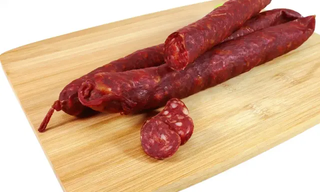 Trzy kawałki pikantnego chorizo na desce. Zastanawiasz się chorizo co to? To aromatyczna, suszona kiełbasa.