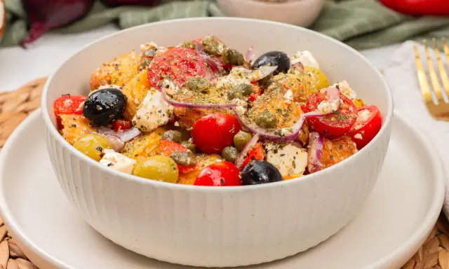 Schüssel mit einem frischen griechischen Kartoffelsalat, garniert mit Oliven, Tomaten, Kapern und Feta.