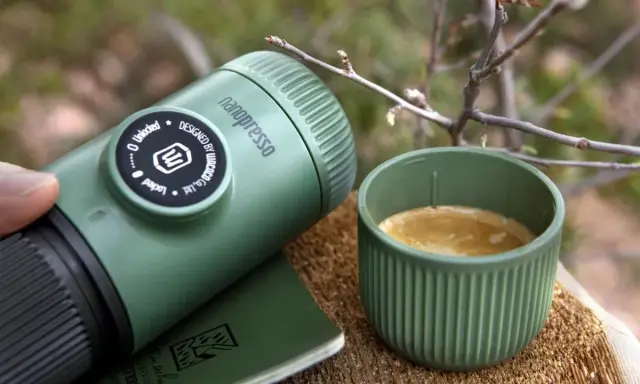 Kawa w górach: nanopresso i filiżanka świeżego espresso na drewnianym pniu, otoczone leśną scenerią.