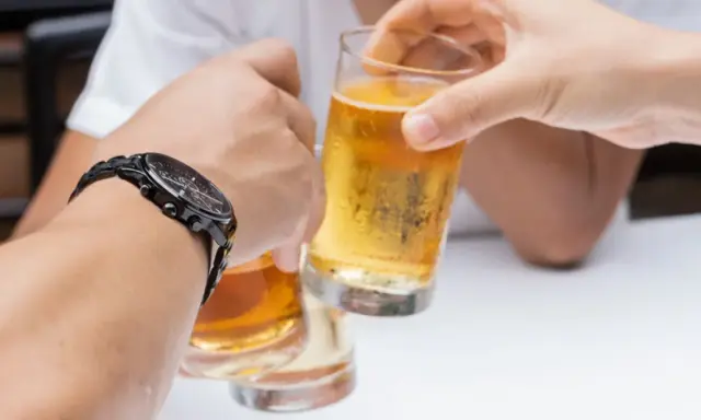 Dwie osoby wznoszą toast piwem. Pytanie: czy chory na raka może pić alkohol?