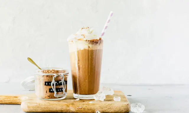 Eiskaffee mit gekochtem Kaffee, zubereitet im Thermomix, gekrönt mit Sahne. Daneben ein Glas mit Eiskaffee-Pulver.