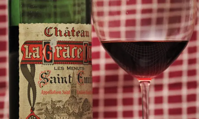 Ein Glas Rotwein neben einer Flasche Château La Grace Dieu, ein Saint-Émilion Grand Cru.