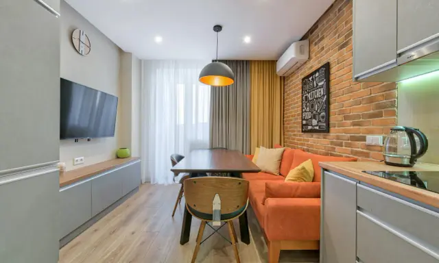 Idée pour aménager salon salle à manger 15m2 : canapé orange, table en bois, mur brique, cuisine moderne.
