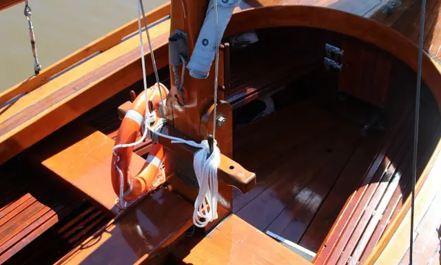 Le bois de bateau verni brille au soleil. Une bouée orange est accrochée, prête pour l'aventure.