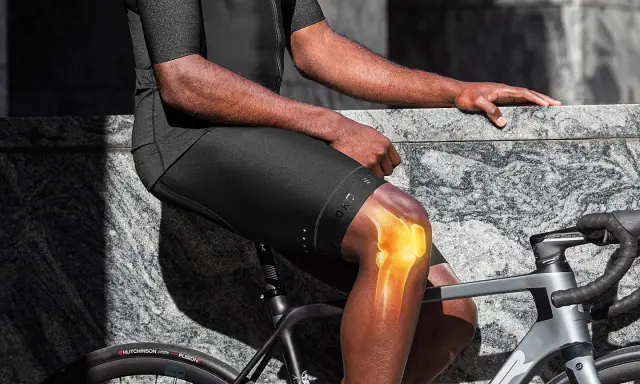 Rowerzysta z podświetlonym kolanem, sugerującym gonartrozę. Jazda na rowerze może być wyzwaniem przy problemach ze stawami.