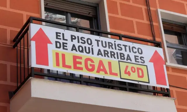 Cartel en balcón: "El piso turístico de aquí arriba es ilegal". Prohibición pisos turísticos.