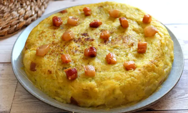 Un delicioso trinxat de la Cerdanya, una tortilla dorada con trocitos de tocino crujiente, lista para disfrutar.