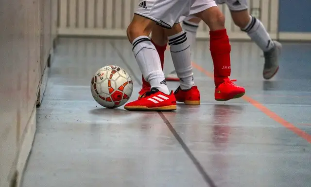 Piłka do futsalu na hali, obok butów zawodników. Tak, w turfy można grać na hali, to właśnie futsal!