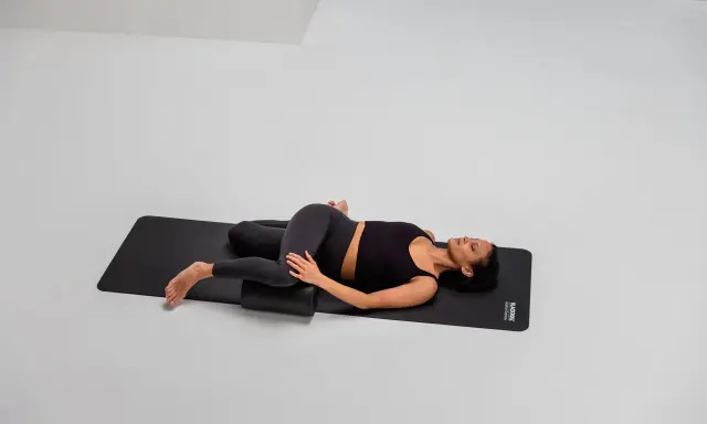 Frau mobilisiert mit Foam Roller die ISG-Region in Rückenlage.