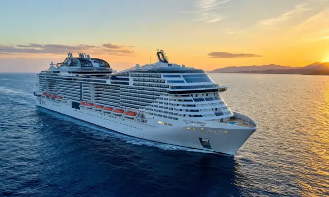 MSC Grandiosa, nave di dimensioni imponenti, solca il mare al tramonto, illuminata dalla luce dorata.