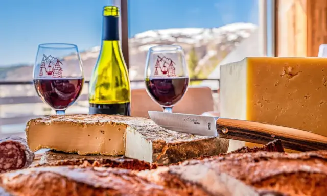 Dégustation de fromages et vin rouge, un aperçu de la gastronomie auvergnate avec vue sur les montagnes enneigées.