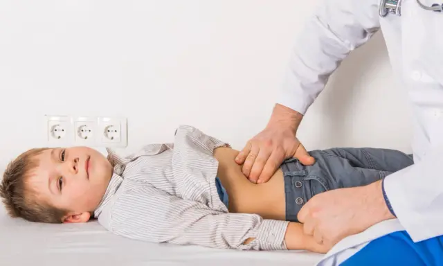 Médico examina el abdomen de un niño con posible gastroenteritis.