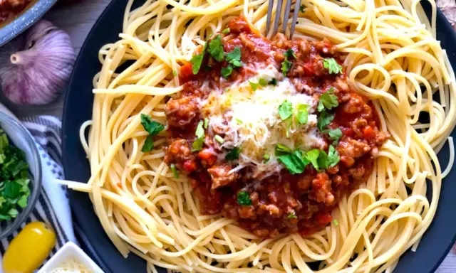 Spaghetti bolognese, prosty przepis. Aromatyczny sos mięsny z mielonym mięsem i pomidorami na złocistym makaronie, posypany serem i natką pietruszki.