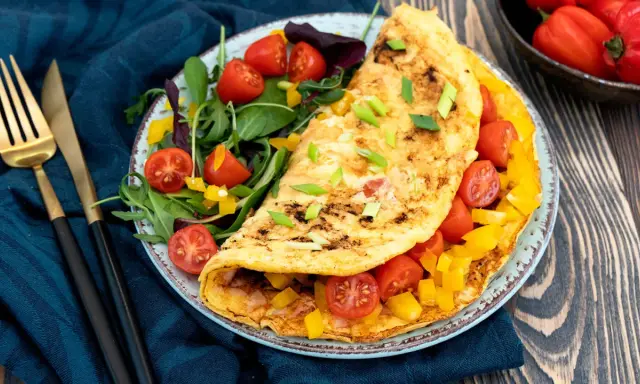 Pyszny omlet fit z pomidorkami i papryką, podany z sałatką. Idealny na zdrowe śniadanie.