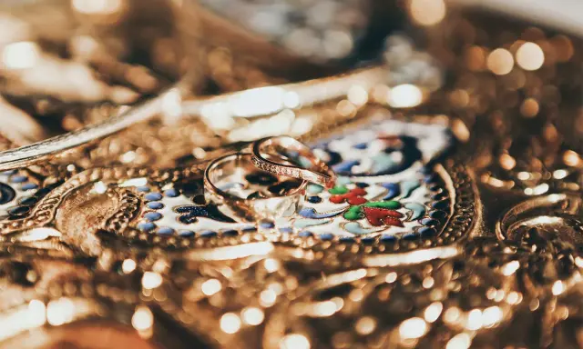 Due fedi nuziali, una con diamanti, su un prezioso scrigno decorato. Un tesoro che ricorda come il platino vale più dell'oro.