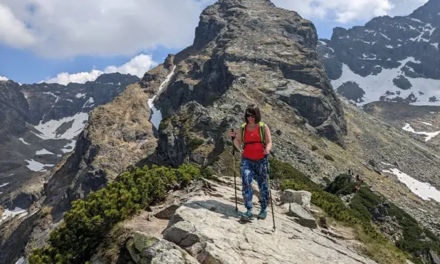 Kobieta z kijkami trekkingowymi na szlaku w Dolinie Gąsienicowej, pod majestatycznym szczytem.