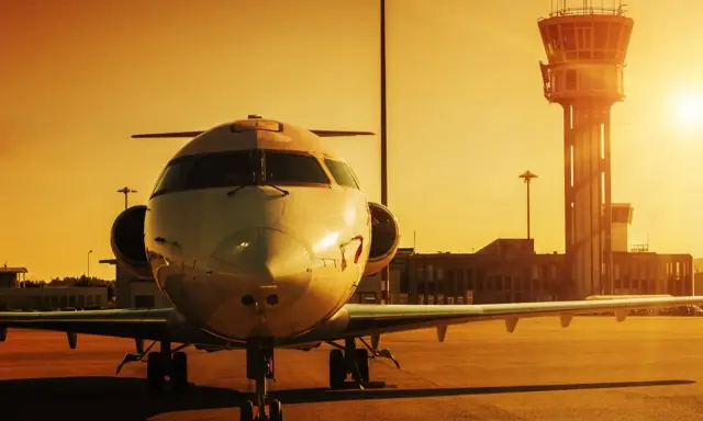 Ett privatjet står parkerat på en flygplats på Cypern vid solnedgången, med kontrolltornet i bakgrunden.