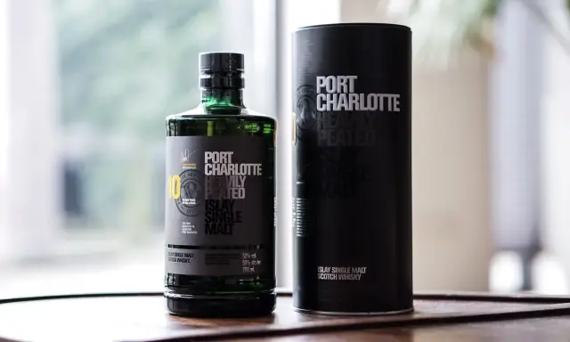 Port Charlotte Heavily Peated 10, whisky single malt z Islay, w zielonej butelce i czarnej tubie.